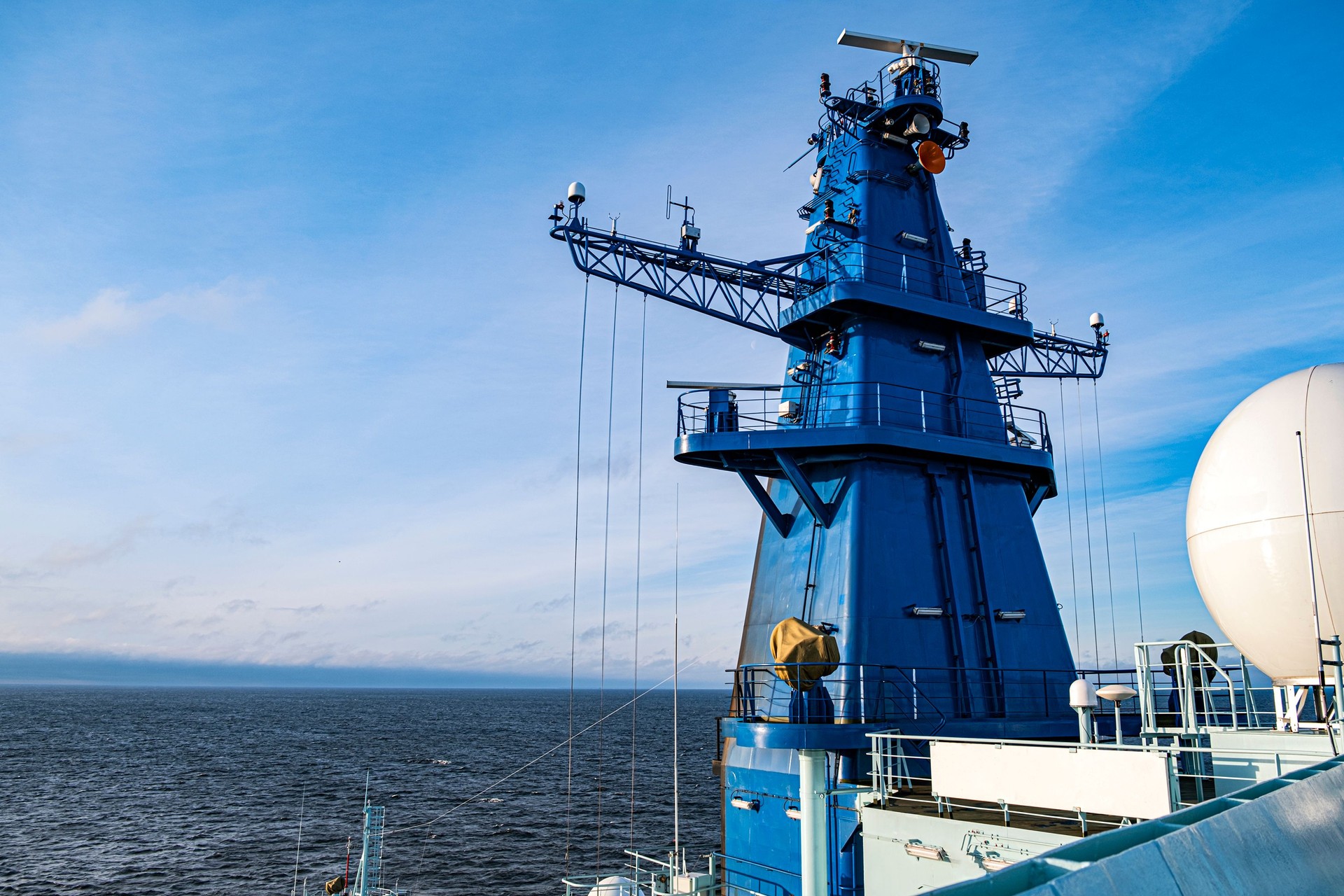 Ships antenna and navigation system in a clear blue sky.